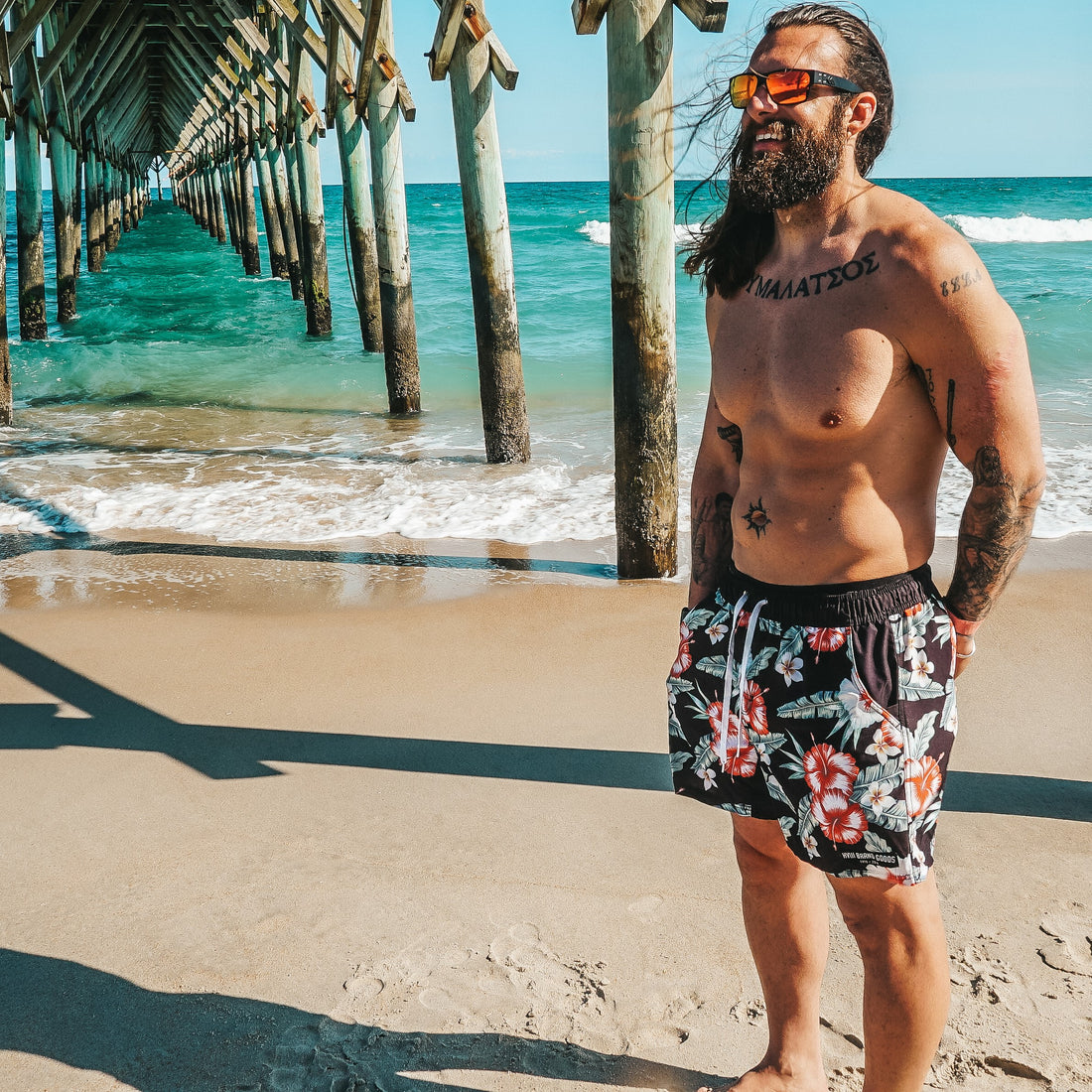 Man on the beach in his swimsuit and sunglasses