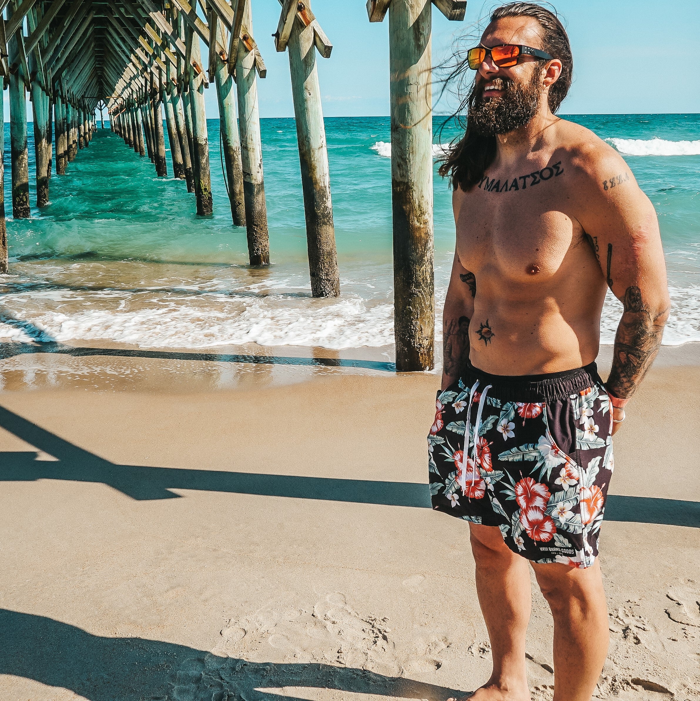 Man on the beach in his swimsuit and sunglasses