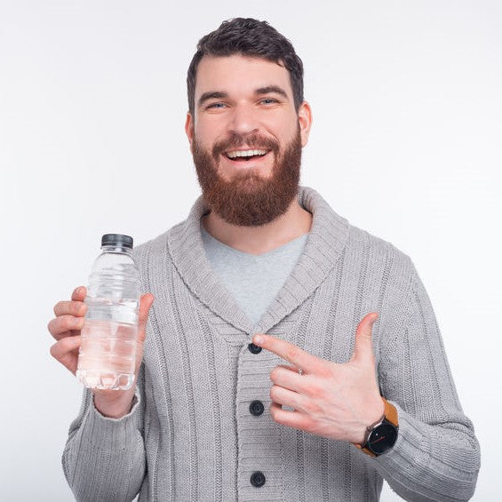 Man with beard smiling and pointing to a bottle of water.