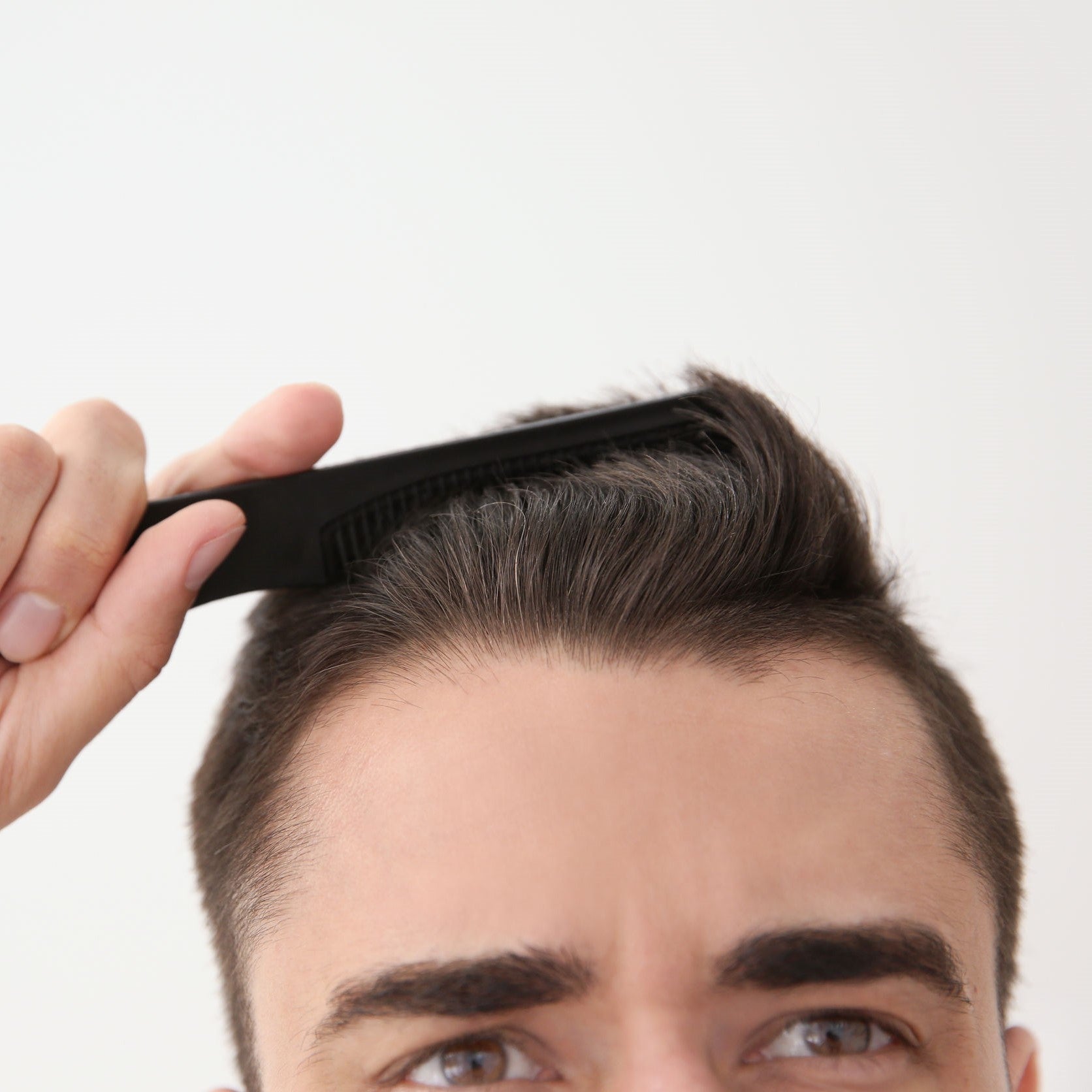 Man combs through his thinning brown hair.