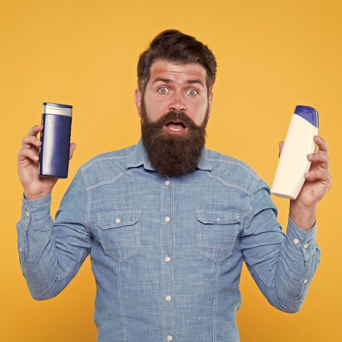 Bearded man holding hair care products in his hands